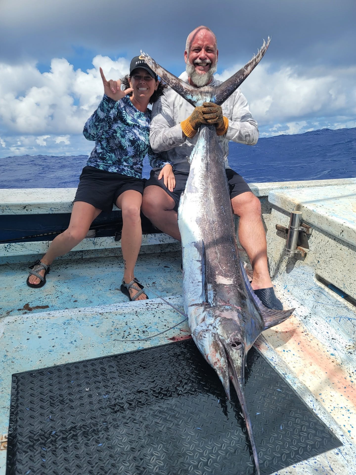 Two guests seated aboard Rainbow Runner behind a large billfish