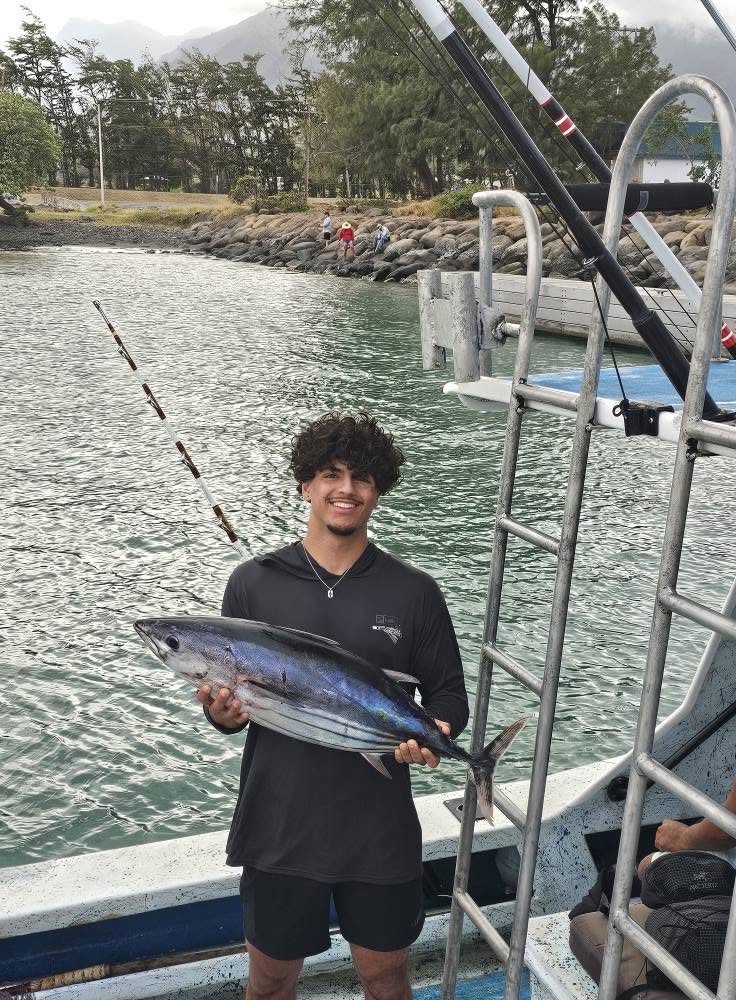Guest holding a catch aboard Rainbow Runner in the harbor