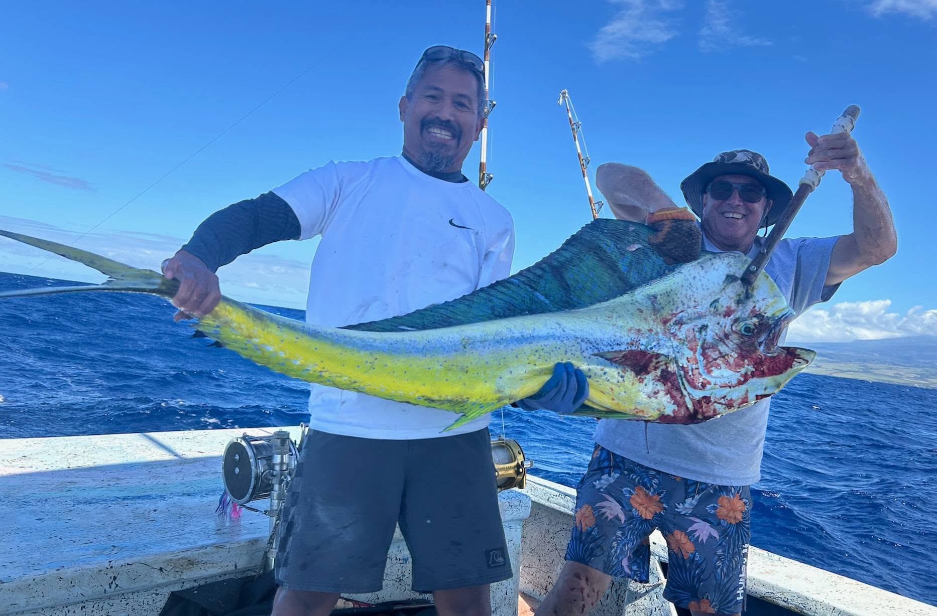 Two people holding a large mahi aboard Rainbow Runner