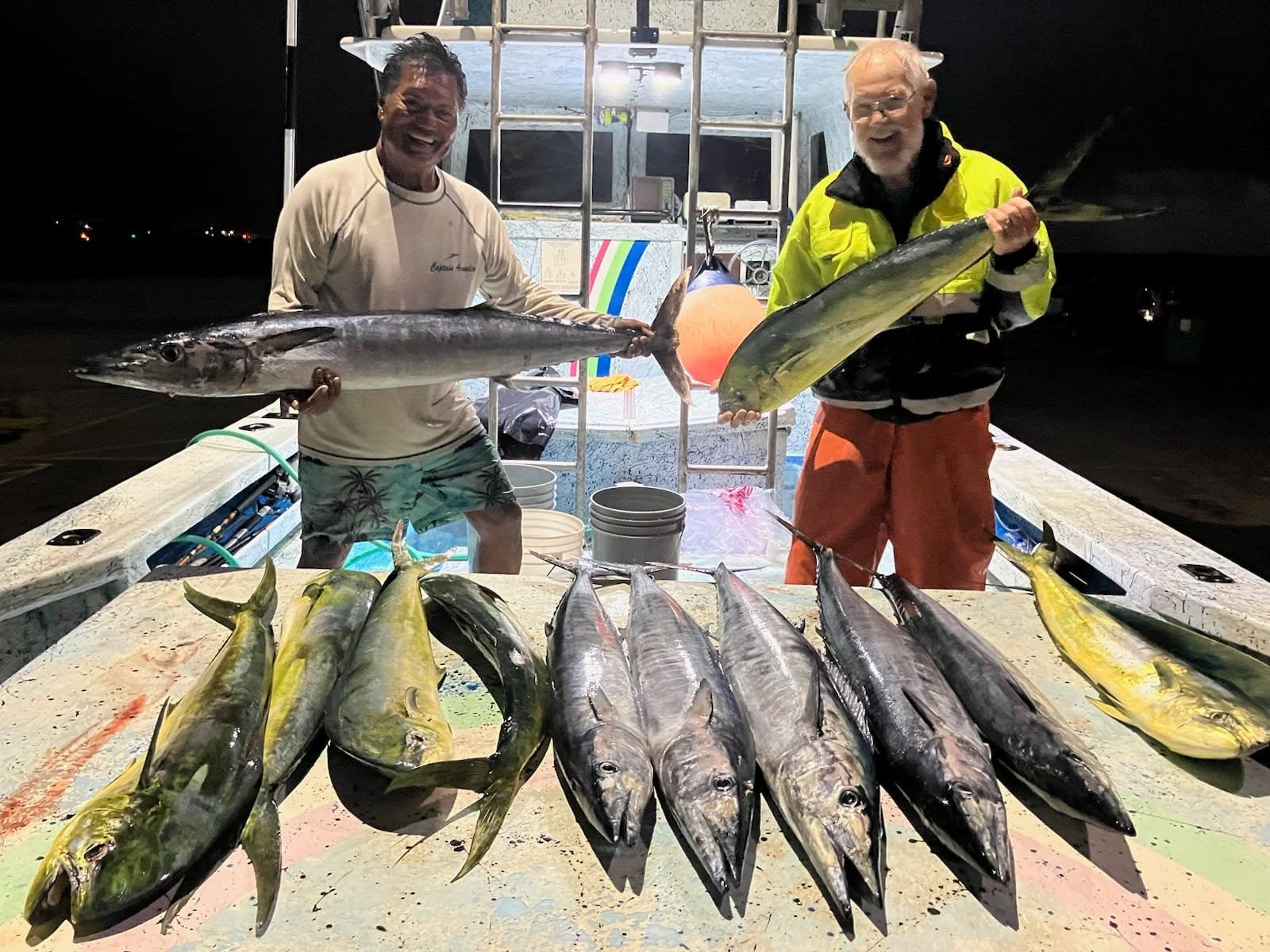 Two people with a mixed catch arranged on Rainbow Runner after dark