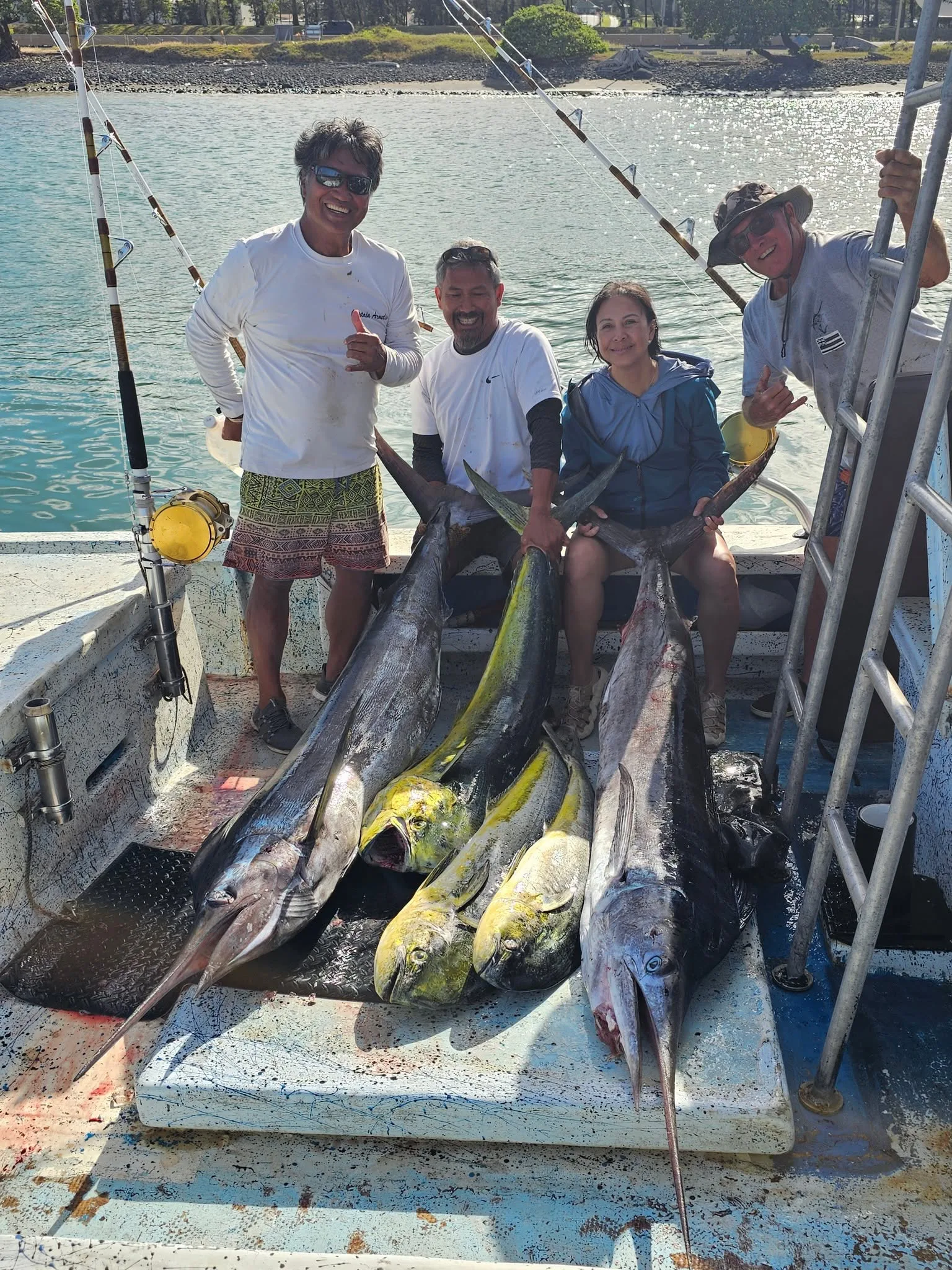 Four people aboard Rainbow Runner behind a varied catch laid across the deck