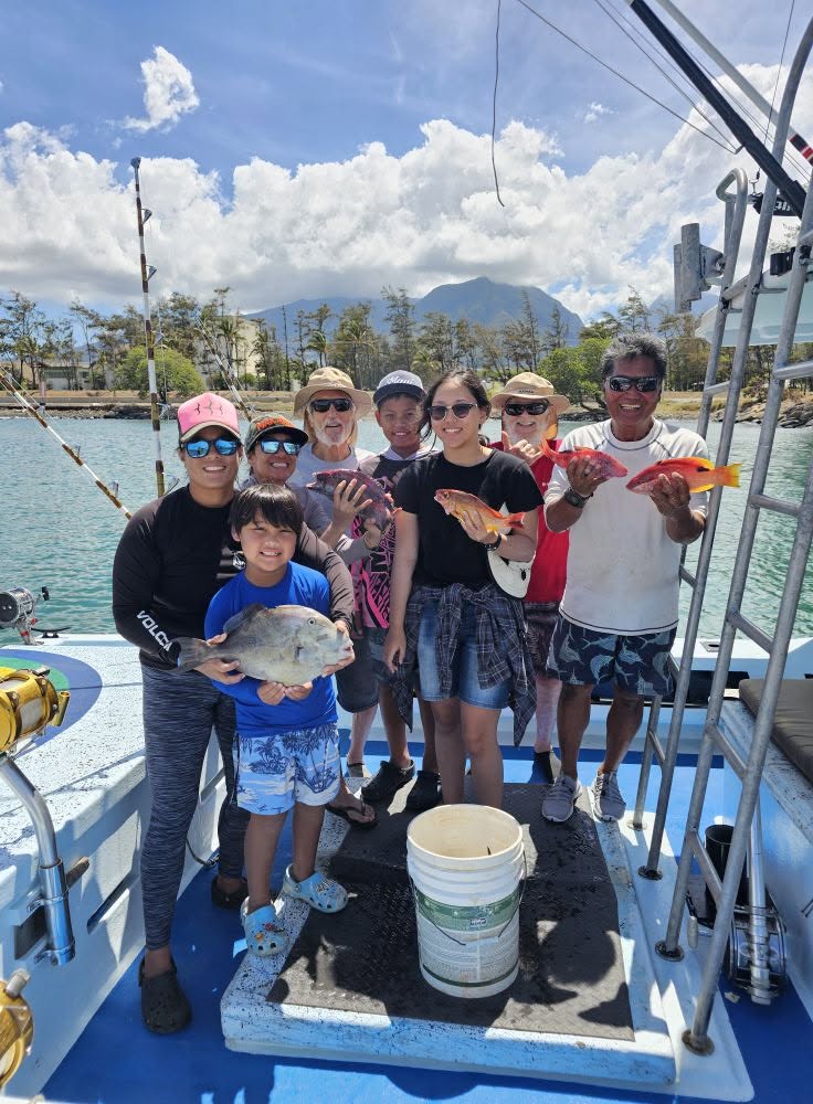 A group aboard Rainbow Runner holding a varied catch at the harbor